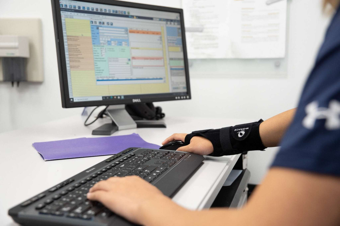 M-Brace Wrist Splint in use while typing at a desk with a computer.