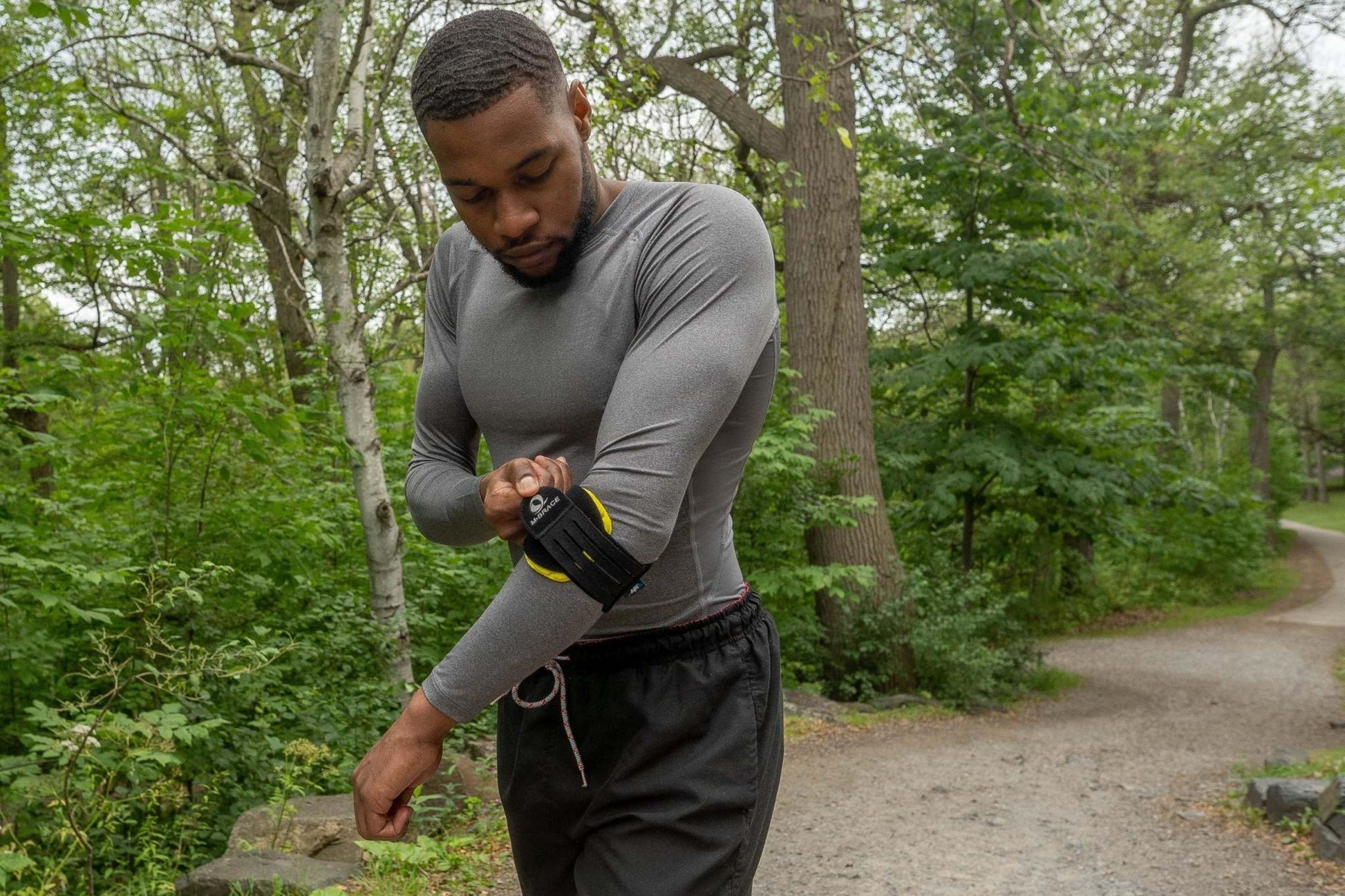 Man adjusting M-Brace Epicondylitis Brace on elbow while outdoors.