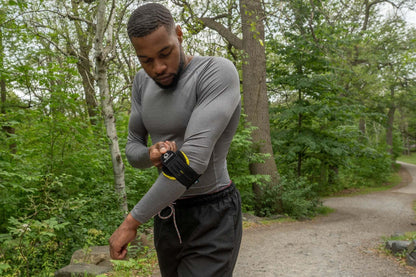 Man adjusting M-Brace Epicondylitis Brace on elbow while outdoors.
