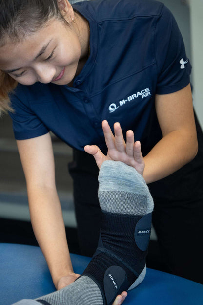 Ankle stabilizer being fitted by a professional, showcasing the M-Brace Strenua Extra Ankle Lock brace.