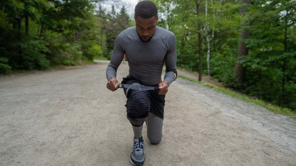 Man adjusting knee stabilizer brace for joint support outdoors.