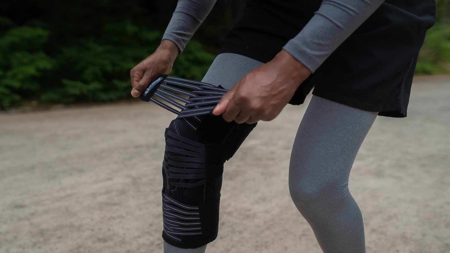 Knee brace being adjusted for joint support and stabilization.