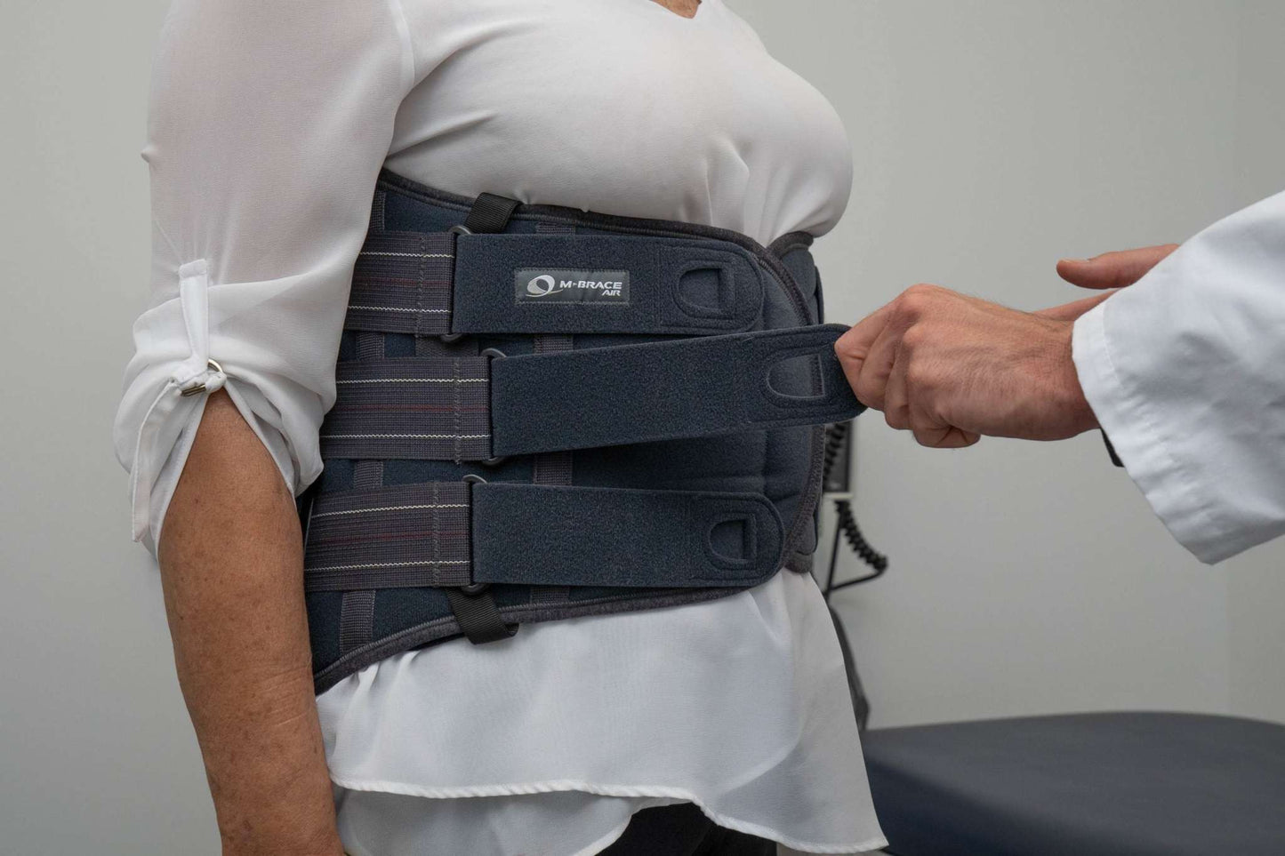 M-Brace Castor Lumbar Sacral Brace being fitted on a person wearing a white shirt.