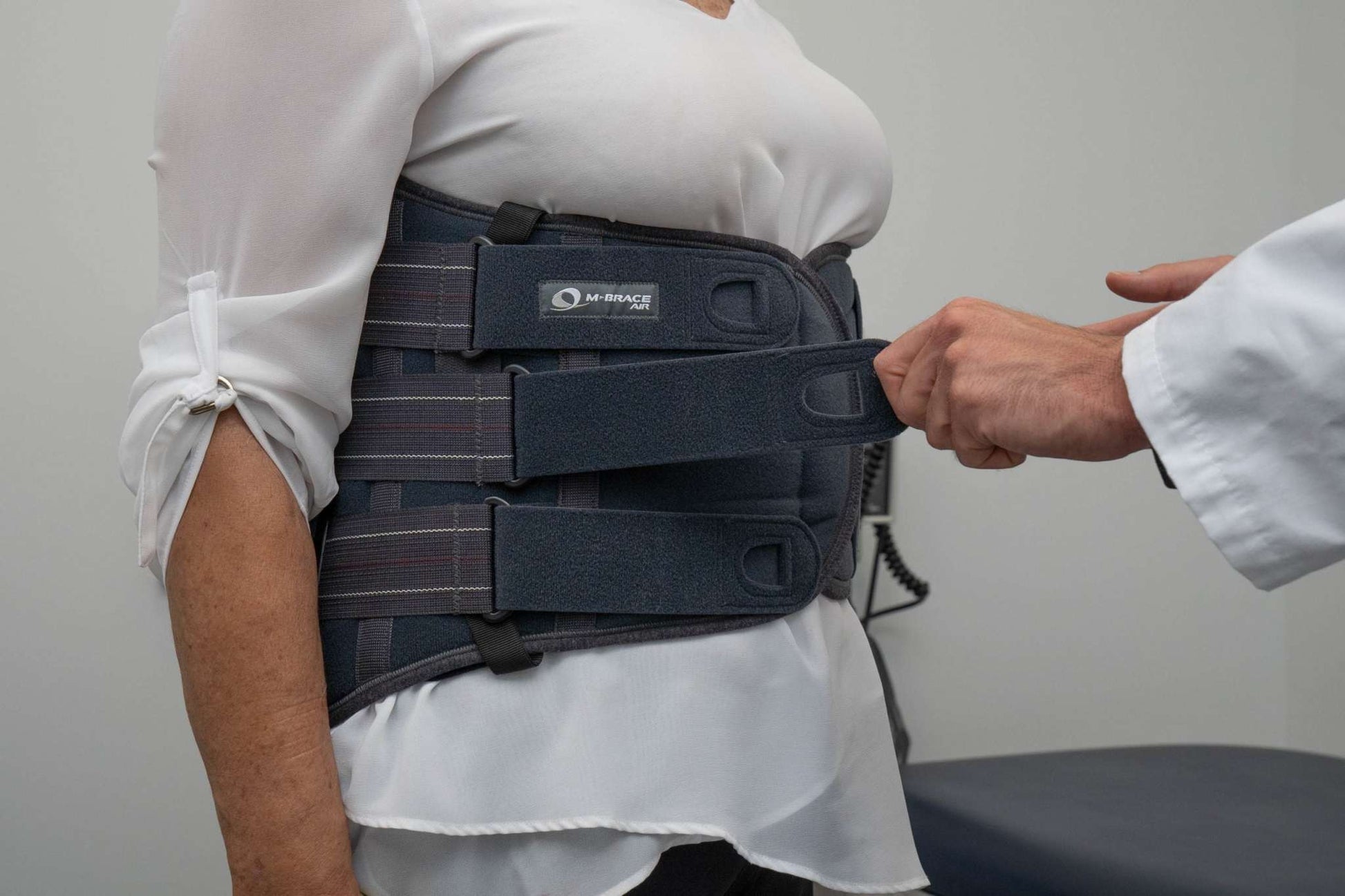 M-Brace Castor Lumbar Sacral Brace being fitted on a person wearing a white shirt.